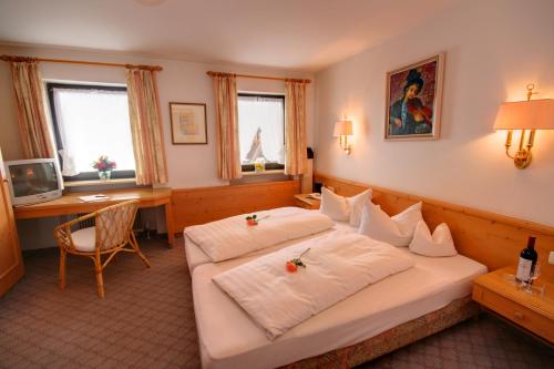 Habitación de hotel con 2 camas y escritorio en Hotel Adler Garni, en Hirschegg