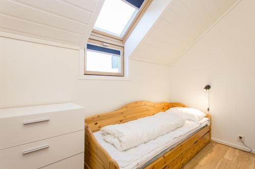 a bedroom with a wooden bed with a skylight at Sjøsanden Ferietun in Mandal