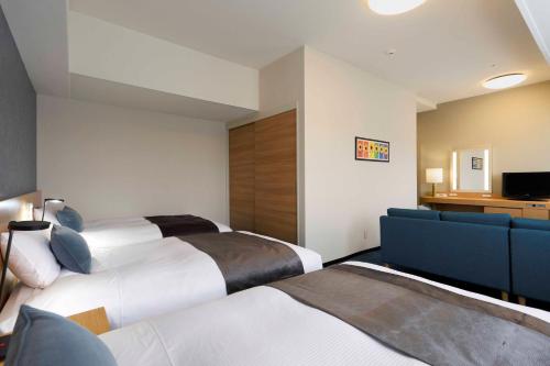 a hotel room with two beds and a couch at Art Hotel Narita in Narita