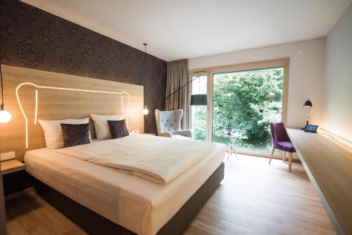 ein Schlafzimmer mit einem großen Bett und einem großen Fenster in der Unterkunft Parkhotel Schillerhain in Kirchheimbolanden