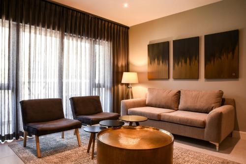 a living room with a couch and two chairs at Mint Hotel Sandhurst in Johannesburg