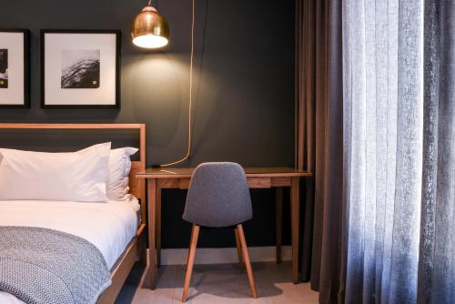 a bedroom with a bed and a desk and a chair at Mint Hotel Sandhurst in Johannesburg