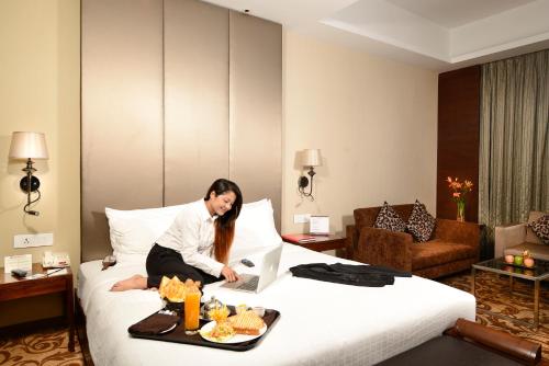 a woman sitting on a bed in a hotel room at Pride Plaza Hotel, Kolkata in Kolkata