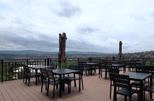 a deck with tables and chairs and umbrellas at Dmall Hotel in Kigali