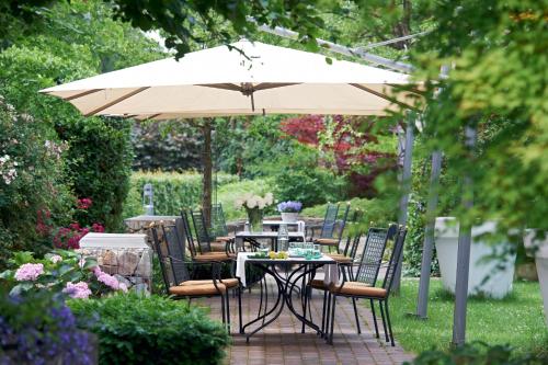 einen Tisch und Stühle unter einem Sonnenschirm in einem Garten in der Unterkunft Mintrops Land Hotel Burgaltendorf in Essen