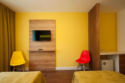 a room with two beds and a tv and two chairs at Hotel Ceramica in Iaşi