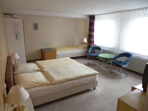 1 Schlafzimmer mit einem Bett, 2 Stühlen und einem Tisch in der Unterkunft Wolfs Hotel in Clausthal-Zellerfeld