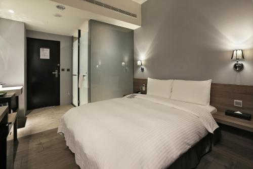 a bedroom with a large white bed and a desk at Miller Inn in Taichung
