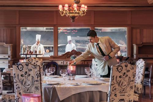 a man is setting a table in a restaurant at Michlifen Resort & Golf in Ifrane