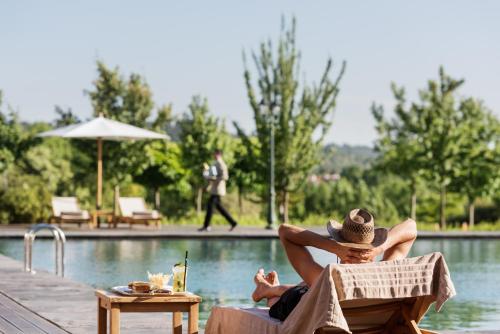 a man laying in a chair next to a swimming pool at Michlifen Resort & Golf in Ifrane