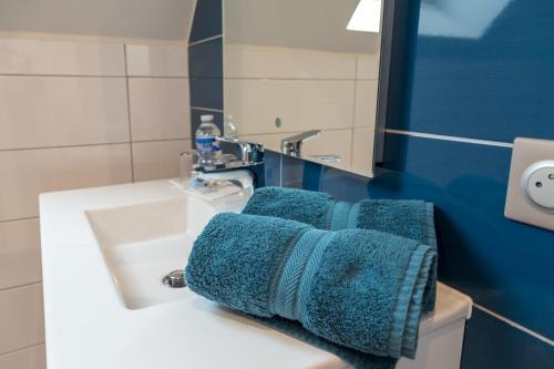 a bathroom with blue towels on a sink at Les Chambres Chez Christine in Ottrott