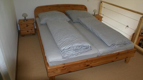 een houten bed met 2 kussens erop bij Übernachten im ehemaligen Zollgebäude in Hauset