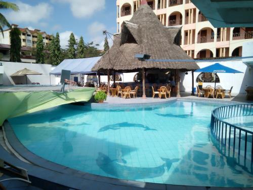 a swimming pool at a hotel with a thatch roof at Lambada Holiday Resort Mombasa in Mtwapa