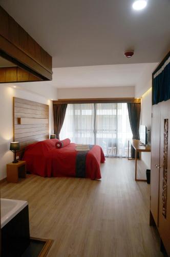 a bedroom with a red bed and a large window at SugarCane Chiang Mai in Chiang Mai