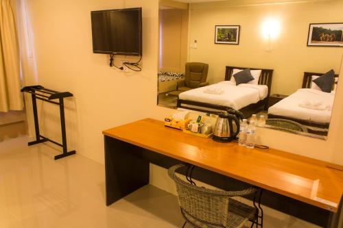 a hotel room with a desk and a bedroom with two beds at Bann Lhong Rak Krabi in Krabi