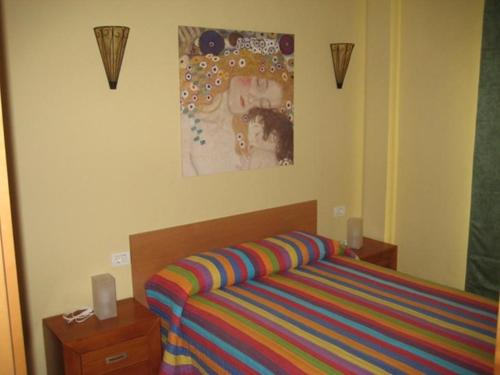 サンタクルス・デ・テネリフェにあるApartamento en Santa Cruzのベッドルーム1室(ベッド1台付)が備わります。壁には絵画が飾られています。