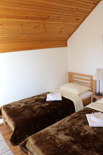 two beds in a room with wooden ceilings at Holiday Home "Iris" near Plitvice Lakes in Rudanovac