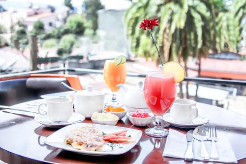 a table with a plate of food and two cocktails at Stay Easy Hotel in Addis Ababa