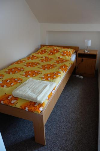 a bed in a room with a yellow blanket and a table at Restaurace ALVI in Ostrava