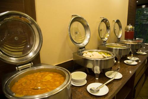 a row of pots of food on a counter at Elite Suites MINT Gomti Nagar in Lucknow