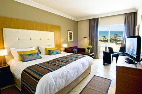 a hotel room with a large bed and a television at Royal Thalassa Monastir in Monastir