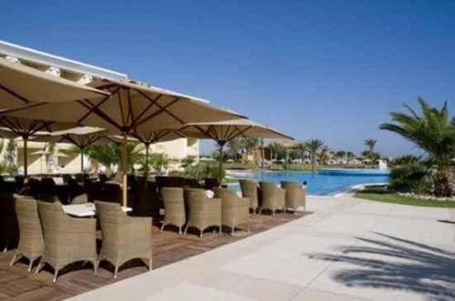 a restaurant with chairs and umbrellas next to a pool at Royal Thalassa Monastir in Monastir