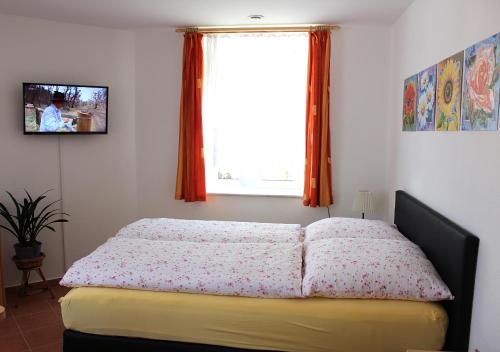 a bedroom with a bed and a window with orange curtains at Wohnen beim Kunsthandwerker in Neuhausen