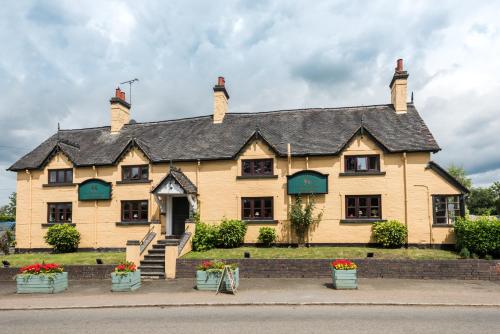 a large yellow house with a black roof at Golden Lion Hotel in Rugby