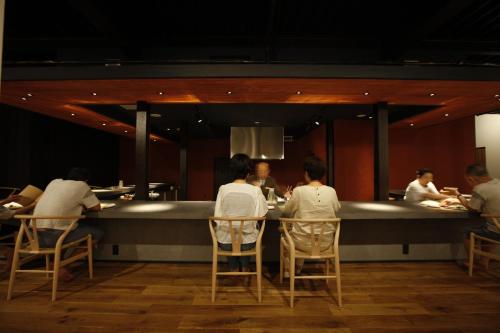 a group of people sitting at a bar in a restaurant at Yamagata The Takinami in Nanyo