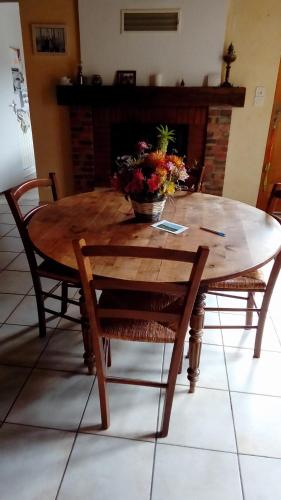une table de salle à manger avec un vase de fleurs dessus dans l'établissement Chambres des Noels, à Faye-d'Anjou