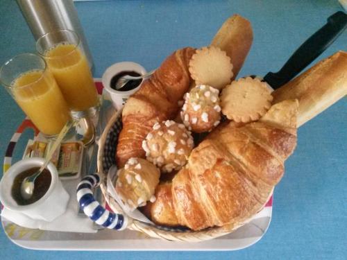 una cesta de pan, cruasanes y un vaso de zumo de naranja en Arroplace en Arromanches-les-Bains