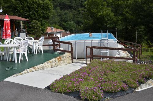 una piscina con sillas blancas, mesa, mesa y sillas en Camping Adamello, en Edolo