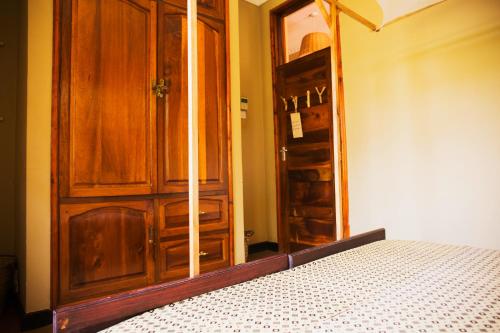 a bedroom with a wooden cabinet and a bed at More Than A Drop in Moshi