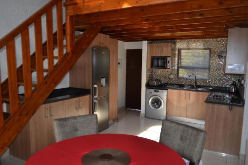 a kitchen with a red table and chairs and a staircase at Alendo Apartments in Johannesburg