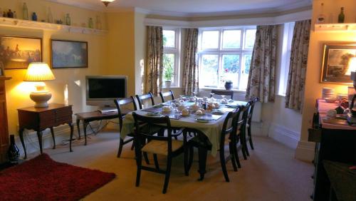 uma sala de jantar com uma mesa com cadeiras e uma televisão em Church Farm Accommodation em Bickenhill