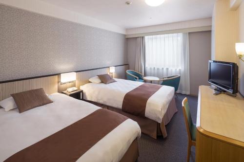 a hotel room with two beds and a flat screen tv at Matsuyama Tokyu REI Hotel in Matsuyama
