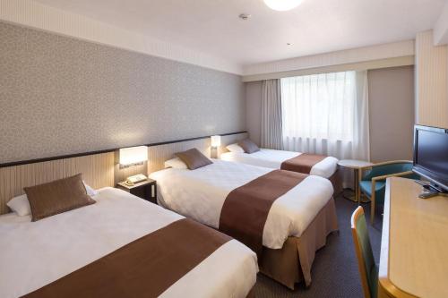 a hotel room with two beds and a flat screen tv at Matsuyama Tokyu REI Hotel in Matsuyama