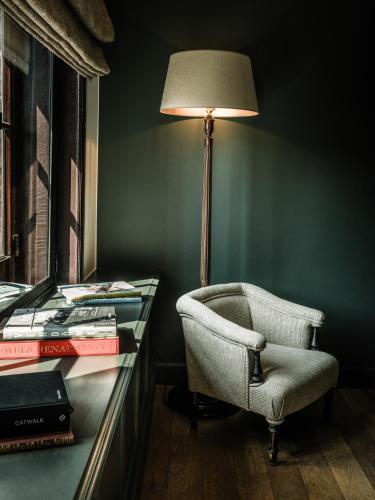 a lamp and a chair next to a desk with books at 1898 The Post in Ghent