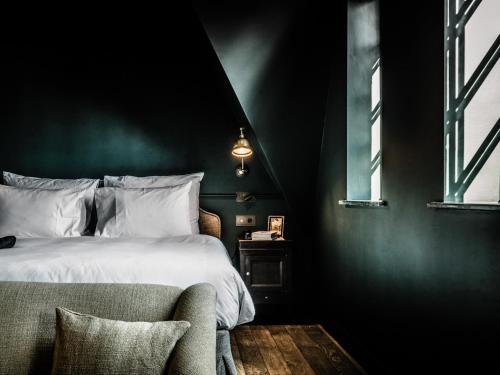a bedroom with a bed and a chair and windows at 1898 The Post in Ghent