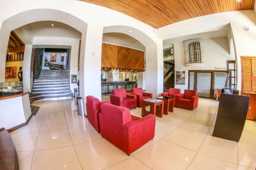 a living room with red chairs and a table at Hotel Fortin Plaza in Oaxaca City