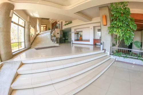 a large lobby with white tile floors and stairs at Hotel Fortin Plaza in Oaxaca City