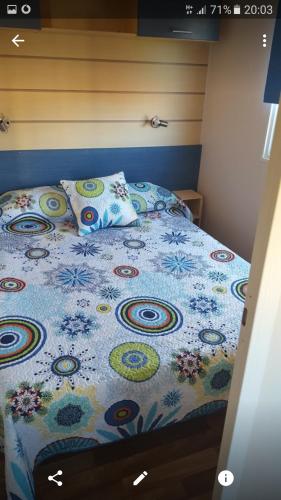 a bed with a colorful comforter and pillows on it at Mobil home in El Palmar