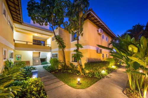 an exterior view of a building with trees and lights at Vitoria Regia Praia Hotel in Porto Seguro