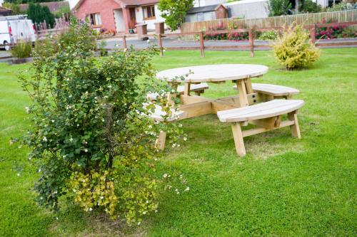 a picnic table and bench in the grass with a bush at The White Swan Inn in Lowick
