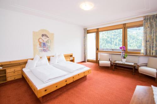 a bedroom with a large white bed and a room with at Das Bergland - Vital & Activity in San Leonardo in Passiria