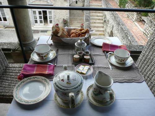 a table with plates and cups and a bowl of food at Demeure des Vieux Bains in Provins