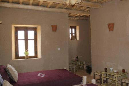 a room with a bed and tables and a window at Kasbah Izoran in Midelt