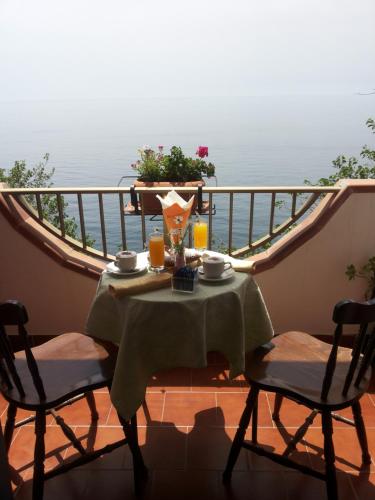 a table and chairs on a balcony with the ocean at Camere Santa Margherita in Santa Margherita-Sant'Alessio Siculo