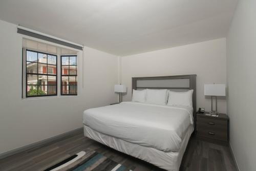 ジョージタウンにあるKing's Hotel & Residencesのベッドと窓のある白い寝室