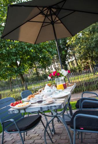 einen Picknicktisch mit Regenschirm und Essen darauf in der Unterkunft De Verloren Sinjoor in Bladel
